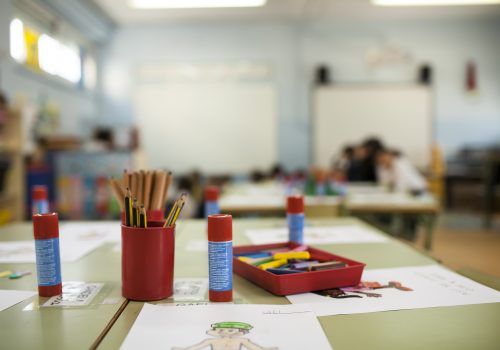 pens, paints and glue stick on table in a primary school class