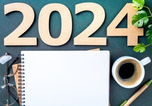 New year resolutions 2024 on desk. 2024 resolutions list with notebook, coffee cup on table. Goals, resolutions, plan, action, checklist concept. New Year 2024 template, copy space